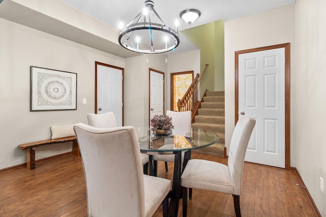 dining room featuring stairway, baseboards, wood-type flooring, and a notable chandelier
