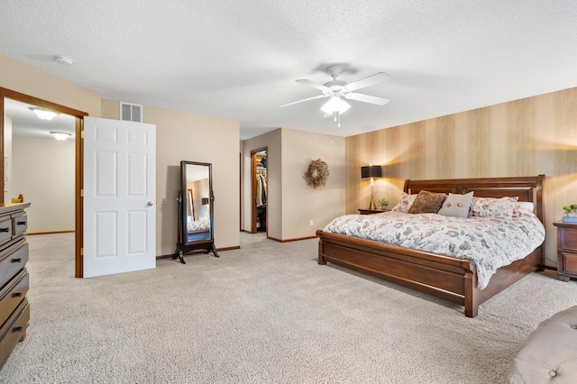 bedroom featuring ceiling fan, light carpet, a textured ceiling, baseboards, and visible vents