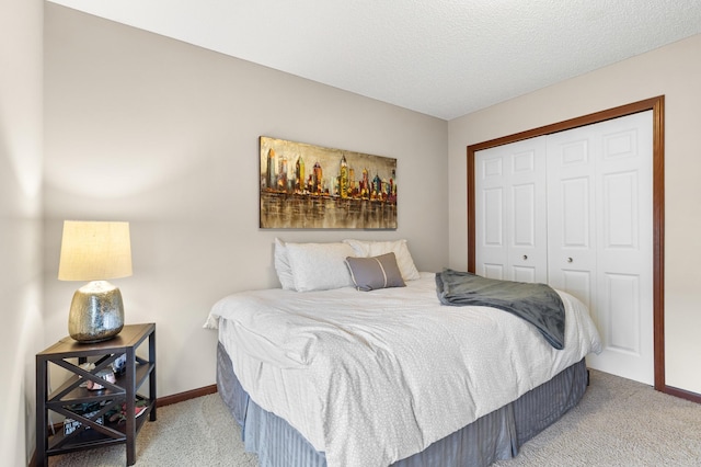 carpeted bedroom featuring a textured ceiling, baseboards, and a closet