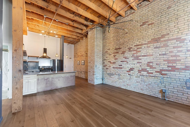kitchen with stainless steel appliances, brick wall, dark wood finished floors, white cabinets, and a sink
