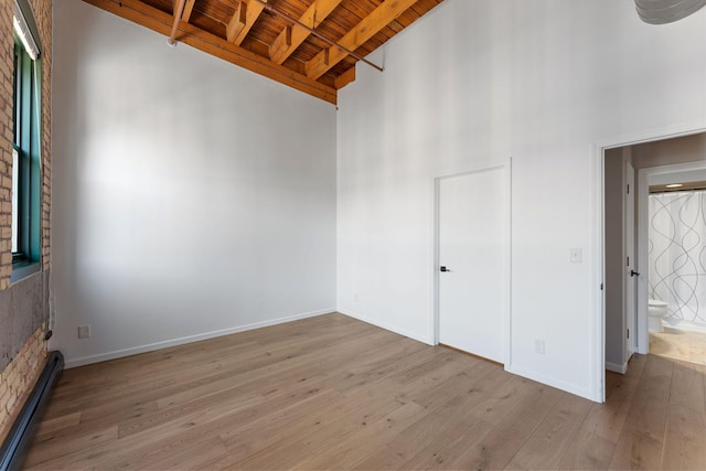 unfurnished room with wooden ceiling, baseboard heating, light wood-type flooring, beamed ceiling, and high vaulted ceiling