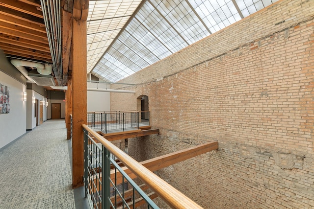 corridor featuring a towering ceiling, brick wall, and carpet flooring