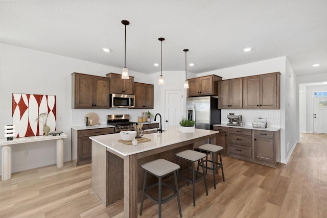 7247 Parquet Ave NE, Otsego, MN 55330 - kitchen with light wood-type flooring, a sink, light countertops, a breakfast bar, and stainless steel appliances