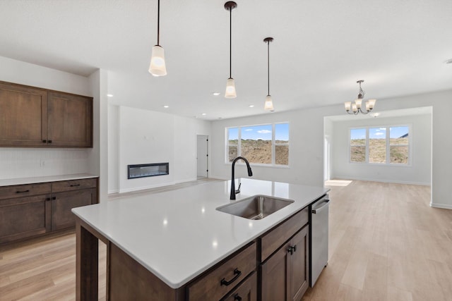 7247 Parquet Ave NE, Otsego, MN 55330 - kitchen with a sink, a notable chandelier, a glass covered fireplace, light wood-style flooring, and open floor plan
