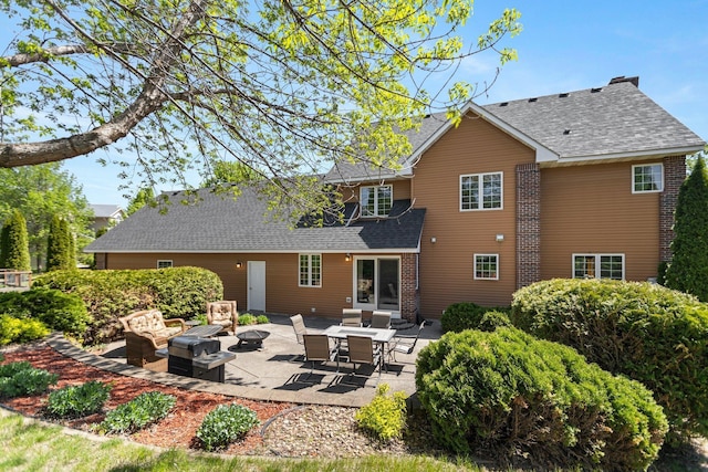 2606 Hulett Ct, Faribault, MN 55021 - back of property featuring an outdoor living space with a fire pit, a patio area, and a shingled roof