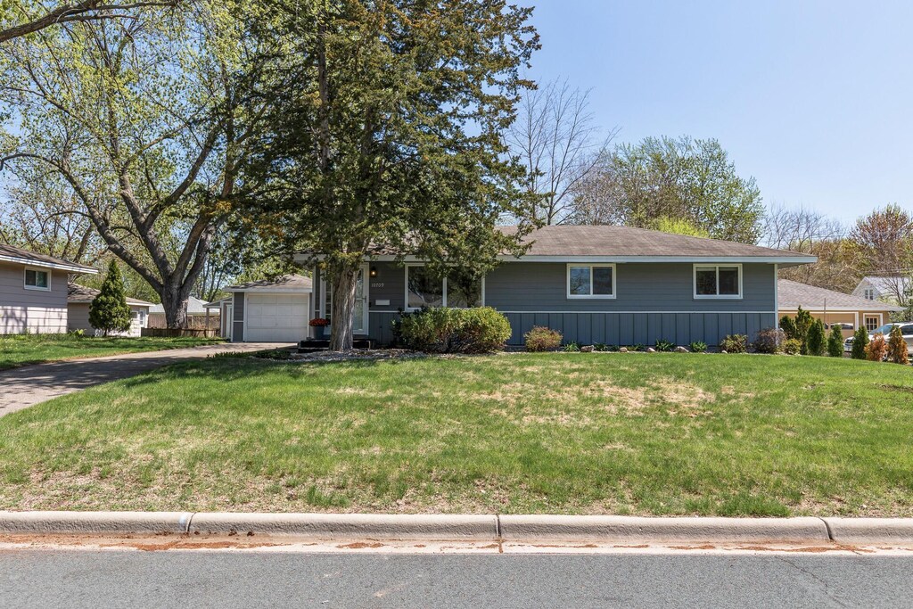 single story home with driveway, a front lawn, and an attached garage