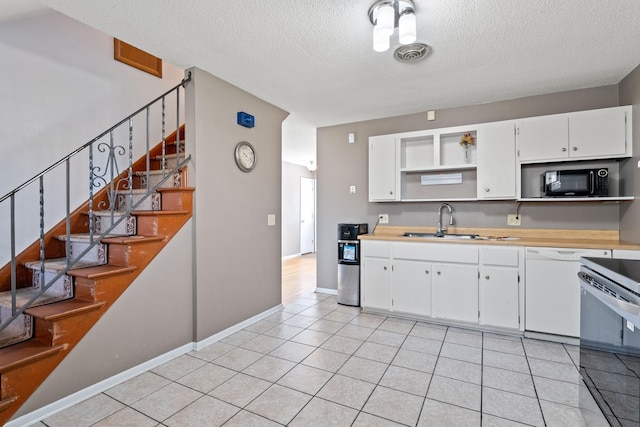 kitchen with open shelves, a textured ceiling, light tile patterned floors, a sink, and dishwasher