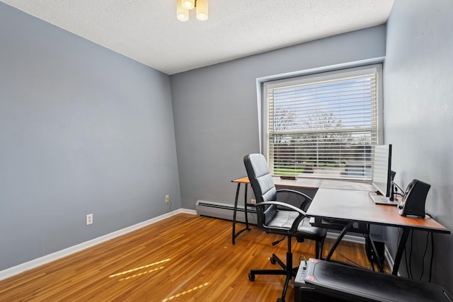 office area featuring a textured ceiling, baseboards, a baseboard heating unit, and wood finished floors