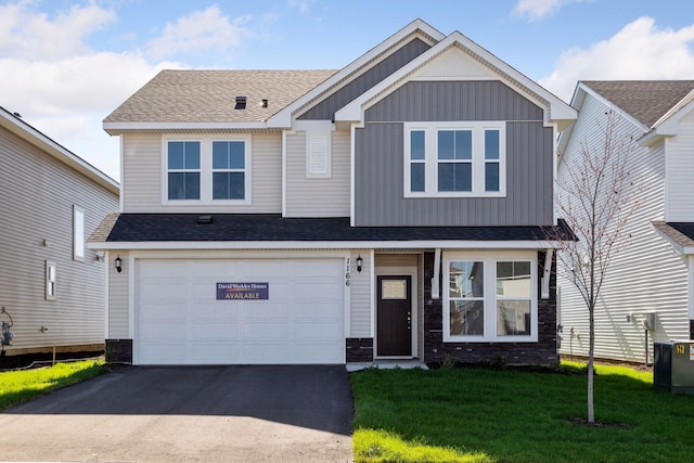 view of front of home with driveway, stone siding, board and batten siding, an attached garage, and a front lawn