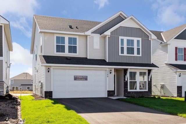 view of front of house with driveway, a garage, board and batten siding, stone siding, and a shingled roof