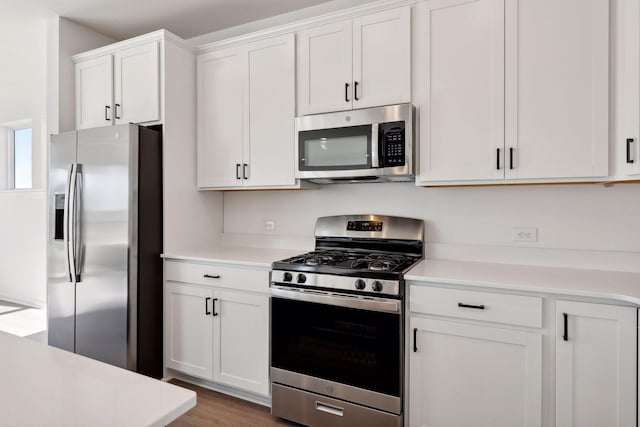 kitchen featuring appliances with stainless steel finishes, light countertops, white cabinetry, and wood finished floors