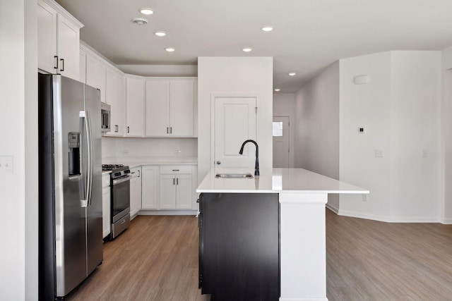 kitchen featuring appliances with stainless steel finishes, light wood-style flooring, an island with sink, light countertops, and recessed lighting