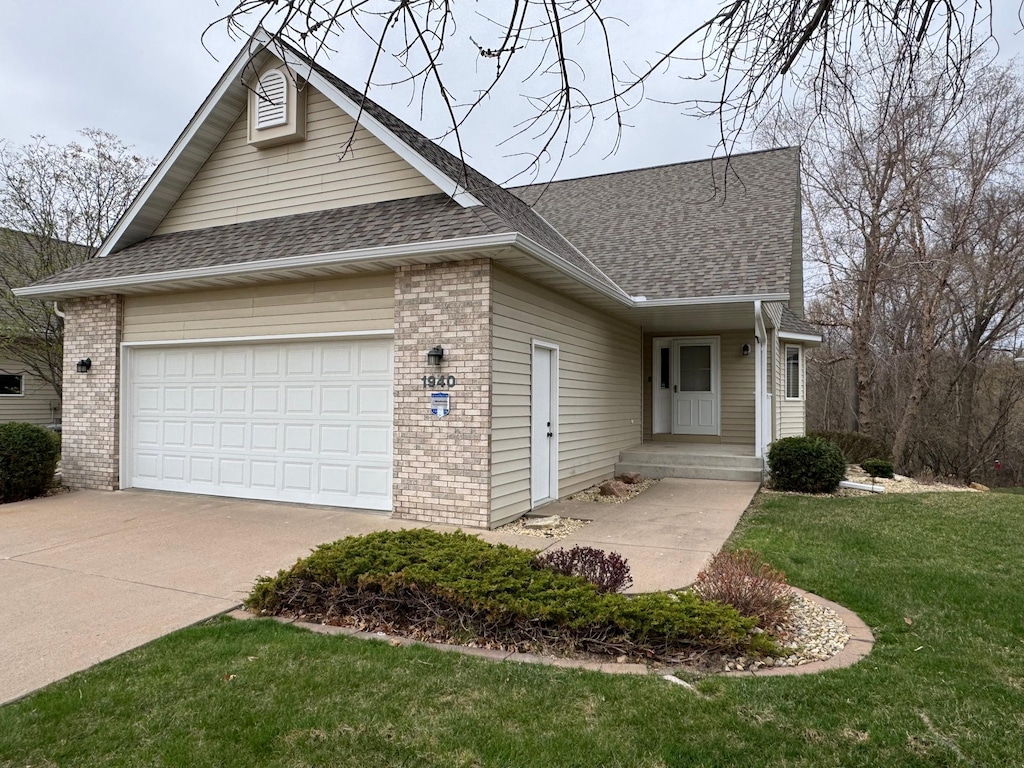 view of front facade with roof with shingles, an attached garage, concrete driveway, and brick siding