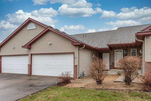 view of front of home with roof with shingles, an attached garage, brick siding, and aphalt driveway