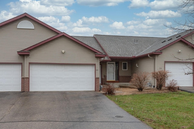 view of front of property with a front lawn, aphalt driveway, roof with shingles, brick siding, and an attached garage