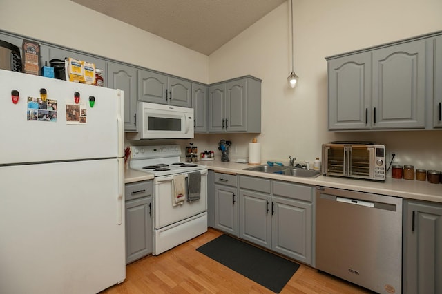 kitchen with a toaster, white appliances, a sink, light wood-style flooring, and gray cabinetry