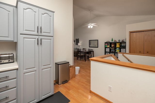 kitchen featuring a ceiling fan, light wood-type flooring, light countertops, a toaster, and lofted ceiling