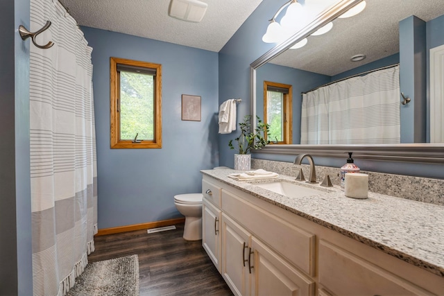 2686 56th Ave, Princeton, MN 55371 - bathroom featuring toilet, wood finished floors, a textured ceiling, vanity, and baseboards