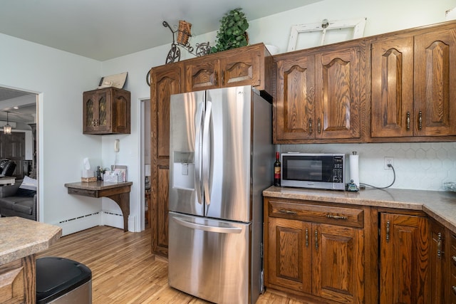 118 Golf Ter, Crookston, MN 56716 - kitchen with appliances with stainless steel finishes, light wood finished floors, light countertops, a baseboard radiator, and backsplash