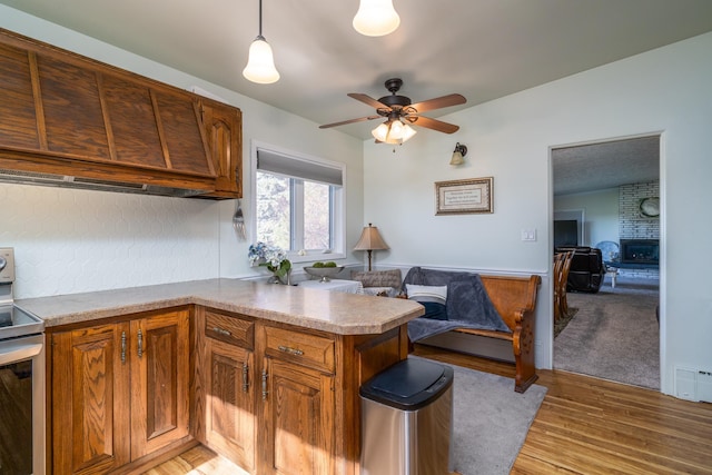 118 Golf Ter, Crookston, MN 56716 - kitchen with brown cabinetry, a ceiling fan, a fireplace, electric stove, and light wood-style flooring