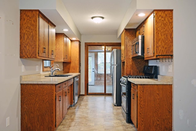 kitchen featuring appliances with stainless steel finishes, brown cabinets, a sink, light countertops, and recessed lighting