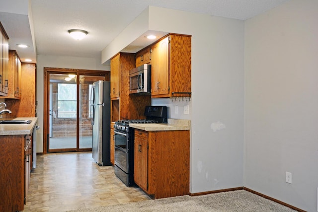 kitchen with baseboards, light countertops, brown cabinets, a sink, and stainless steel appliances