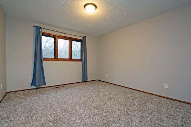 spare room featuring carpet flooring, a textured ceiling, and baseboards