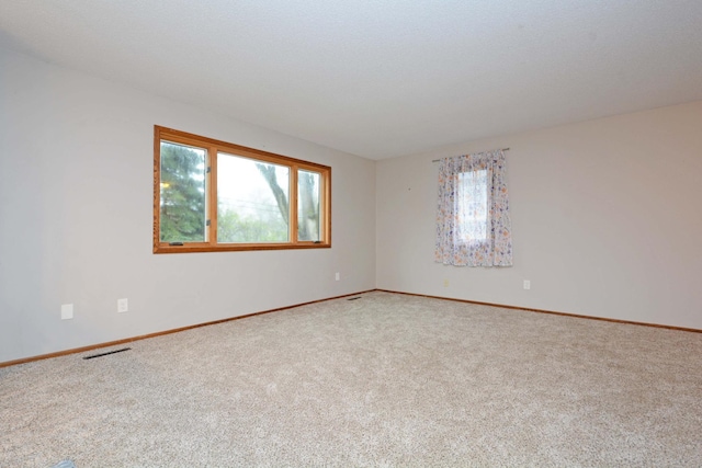 carpeted empty room with baseboards and visible vents