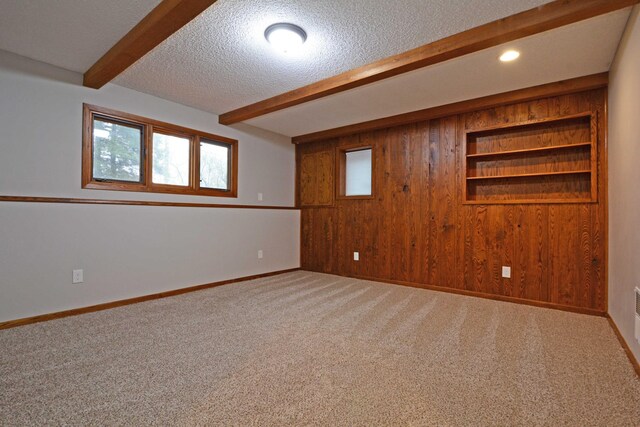 spare room with carpet floors, a textured ceiling, a wealth of natural light, and beamed ceiling