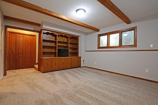 interior space featuring carpet floors, a textured ceiling, baseboards, and beam ceiling