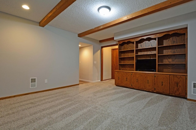 unfurnished living room featuring visible vents, baseboards, beam ceiling, and light carpet