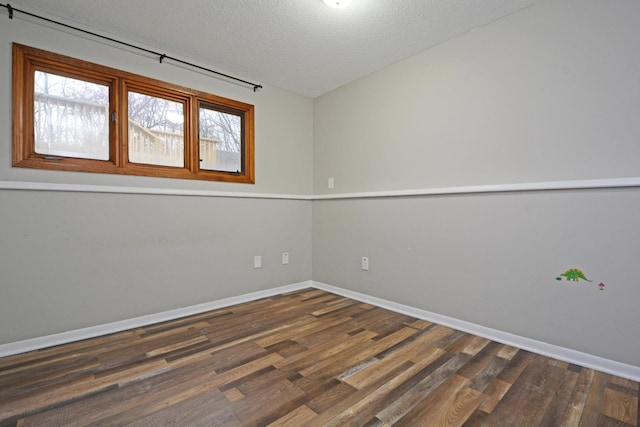 empty room with baseboards, dark wood-style flooring, and a textured ceiling