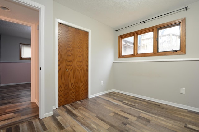 unfurnished bedroom featuring baseboards, a closet, and wood finished floors