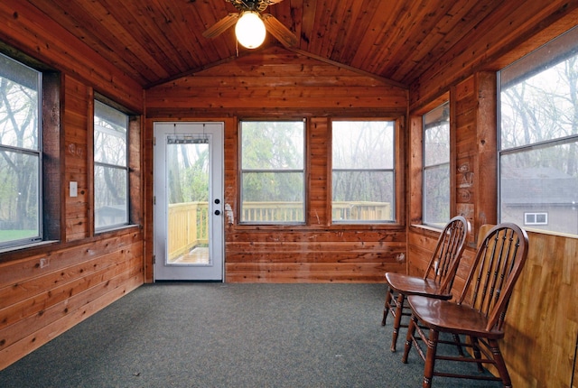 sunroom featuring wood walls and vaulted ceiling