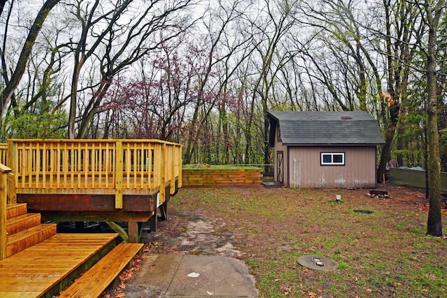 view of yard featuring an outdoor structure, a wooden deck, and a shed