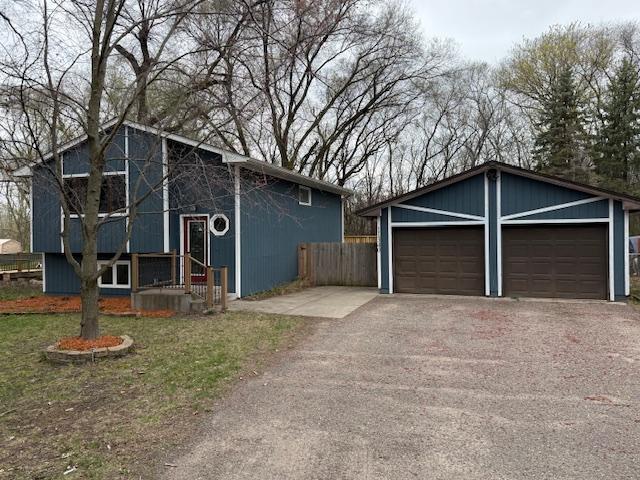 view of front of property featuring fence, an outdoor structure, and driveway