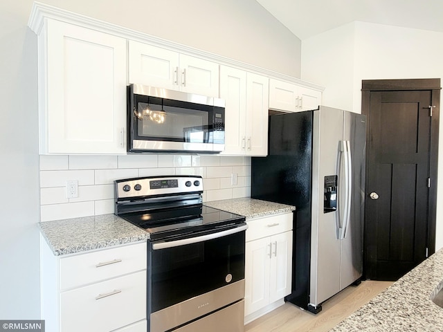 kitchen featuring decorative backsplash, light stone counters, light wood finished floors, stainless steel appliances, and white cabinetry