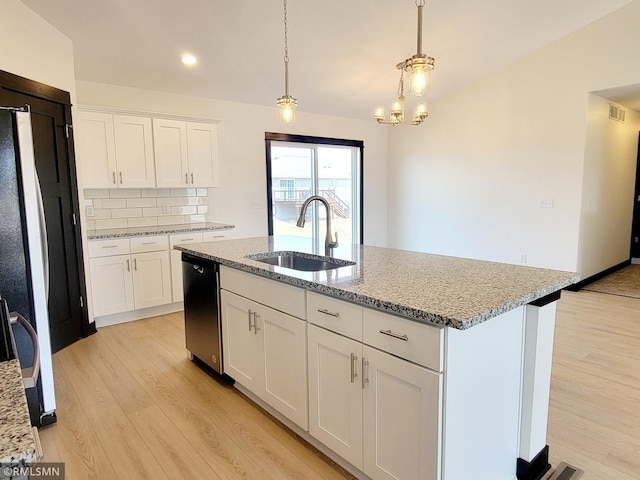 kitchen with dishwasher, light stone countertops, a sink, and light wood-type flooring