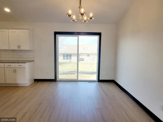unfurnished dining area with an inviting chandelier, baseboards, recessed lighting, and light wood finished floors