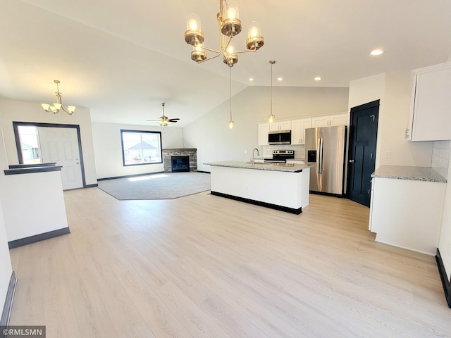 kitchen with appliances with stainless steel finishes, a fireplace, a sink, open floor plan, and lofted ceiling