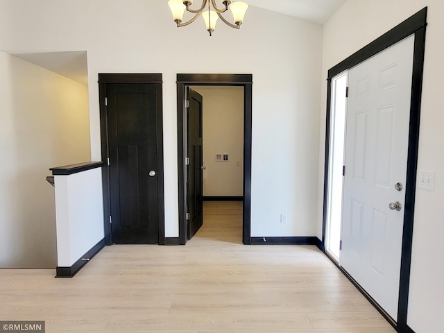 interior space featuring baseboards, light wood-style flooring, and a notable chandelier