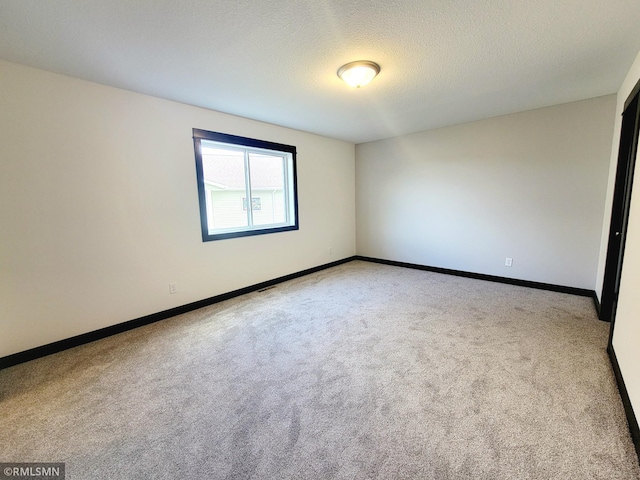 carpeted empty room featuring baseboards and a textured ceiling