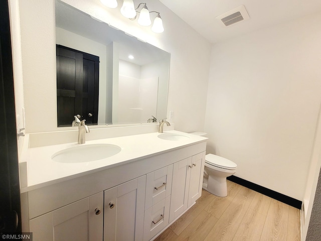 bathroom with visible vents, a sink, wood finished floors, and toilet