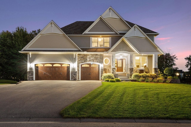 craftsman-style house featuring a garage, a front yard, driveway, and stone siding