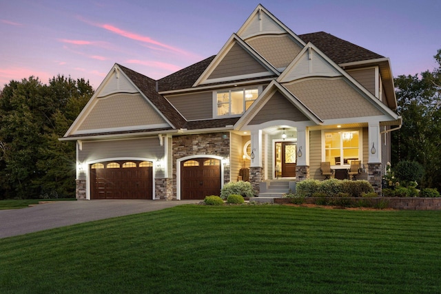 craftsman house featuring a porch, driveway, a front yard, an attached garage, and stone siding
