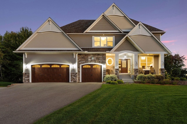 craftsman inspired home with a lawn, driveway, and stone siding