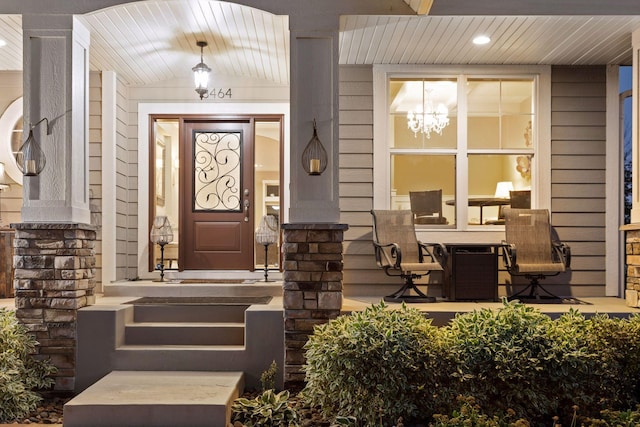 doorway to property with a porch and stone siding