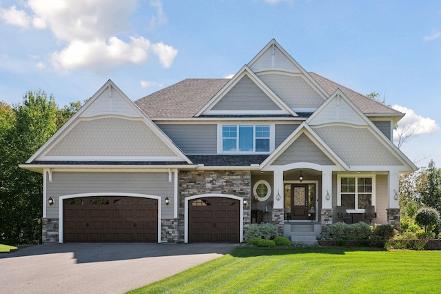 craftsman-style home with a front lawn, driveway, stone siding, and covered porch