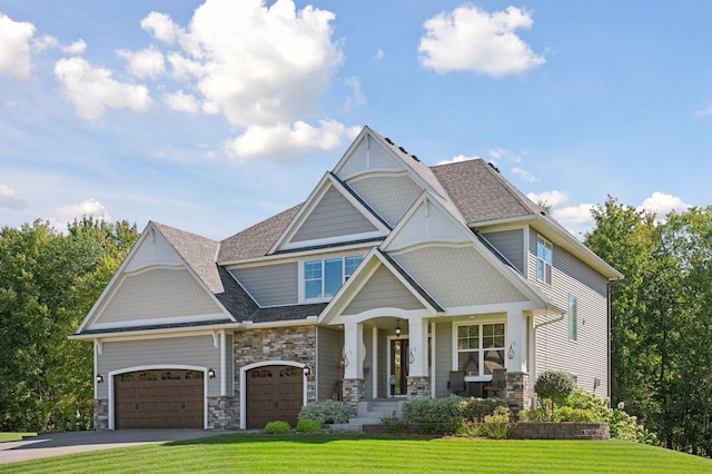 craftsman-style home featuring a front lawn, stone siding, covered porch, and driveway