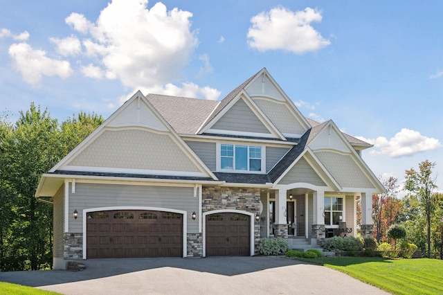 craftsman inspired home with stone siding, a front yard, a porch, and aphalt driveway